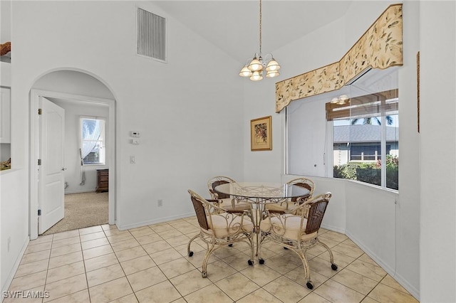 dining area with light tile patterned floors, high vaulted ceiling, and a chandelier