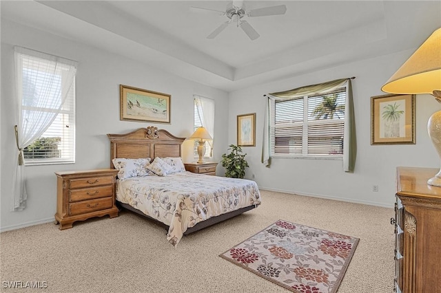 carpeted bedroom featuring a raised ceiling and ceiling fan