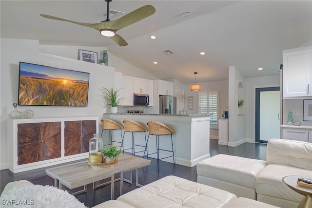 living room with ceiling fan, dark wood-type flooring, and vaulted ceiling