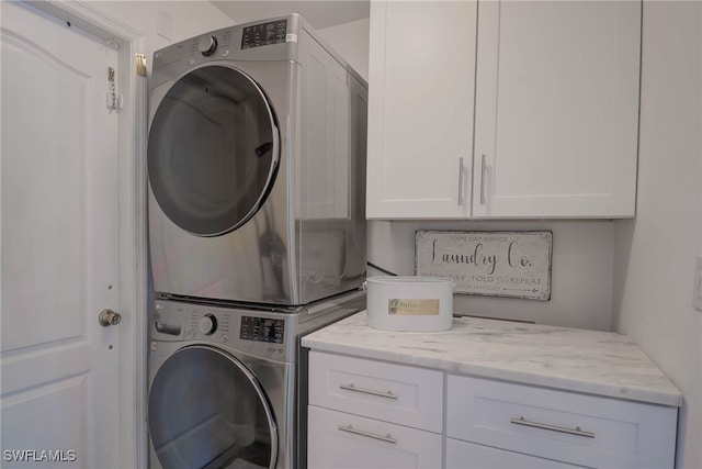 washroom with stacked washer / dryer and cabinets