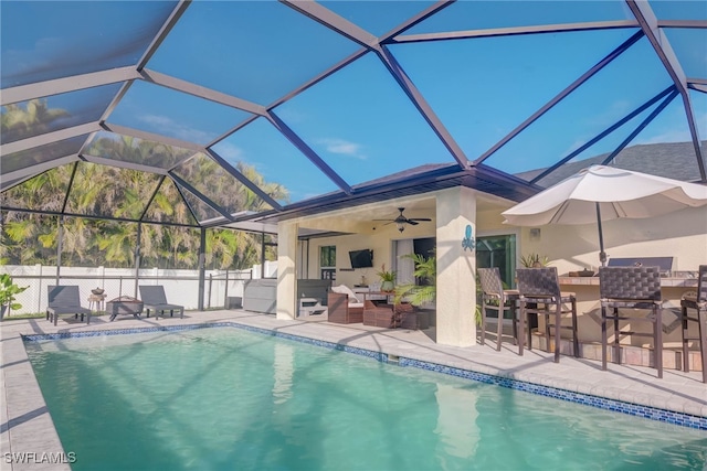 view of swimming pool featuring an outdoor hangout area, ceiling fan, a bar, glass enclosure, and a patio area