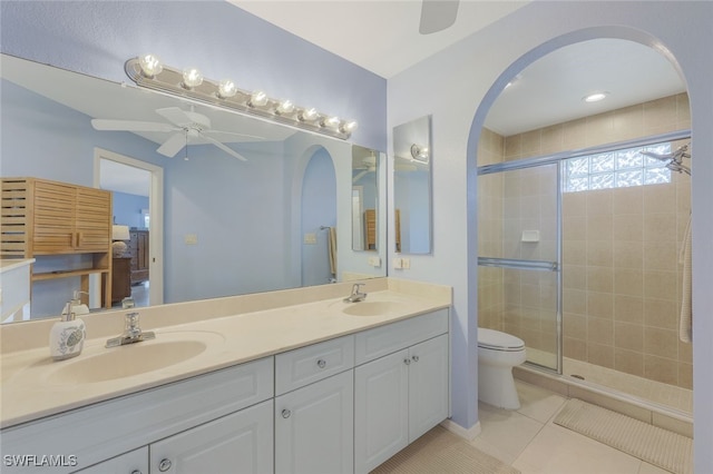 bathroom featuring a shower with shower door, tile patterned flooring, vanity, toilet, and ceiling fan