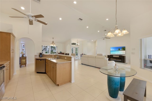 kitchen featuring a center island with sink, appliances with stainless steel finishes, decorative light fixtures, light brown cabinetry, and sink