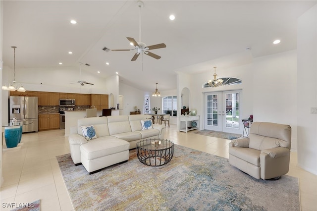 tiled living room featuring ceiling fan with notable chandelier, french doors, and high vaulted ceiling