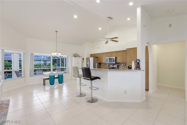 kitchen with kitchen peninsula, stainless steel appliances, tasteful backsplash, high vaulted ceiling, and light stone countertops