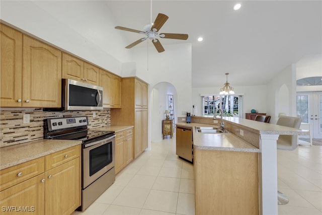 kitchen with appliances with stainless steel finishes, tasteful backsplash, decorative light fixtures, a breakfast bar, and sink