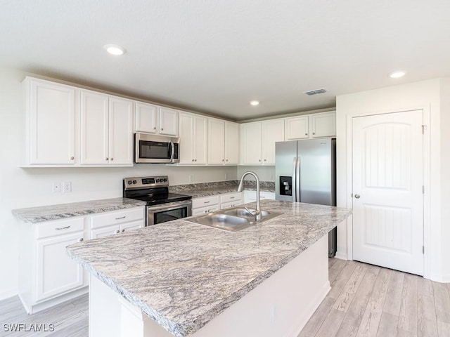 kitchen with sink, stainless steel appliances, white cabinets, and a kitchen island with sink