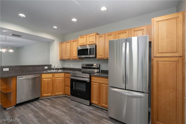 kitchen with sink, stainless steel appliances, dark hardwood / wood-style flooring, kitchen peninsula, and a chandelier