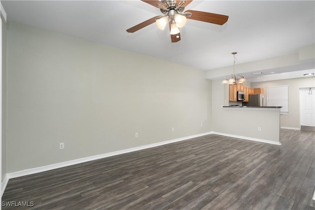 unfurnished living room featuring ceiling fan with notable chandelier and dark hardwood / wood-style floors