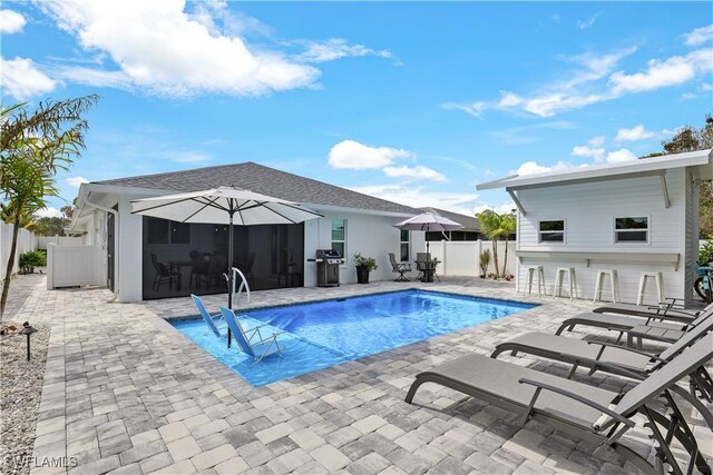 view of swimming pool with a patio, an outdoor bar, and grilling area