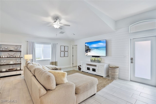 living room featuring ceiling fan and wood walls