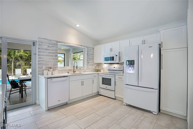 kitchen featuring lofted ceiling, white appliances, white cabinets, sink, and tasteful backsplash