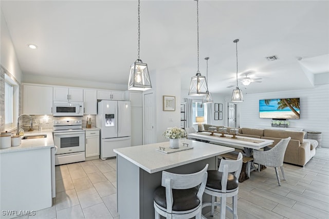 kitchen with sink, white cabinets, pendant lighting, and white appliances