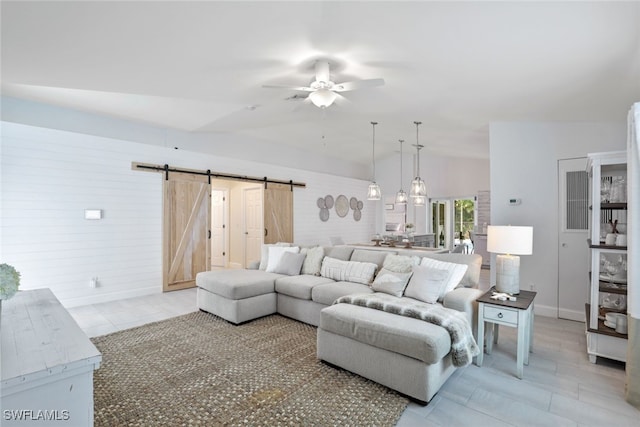 living room with a barn door, ceiling fan, light tile patterned floors, and lofted ceiling