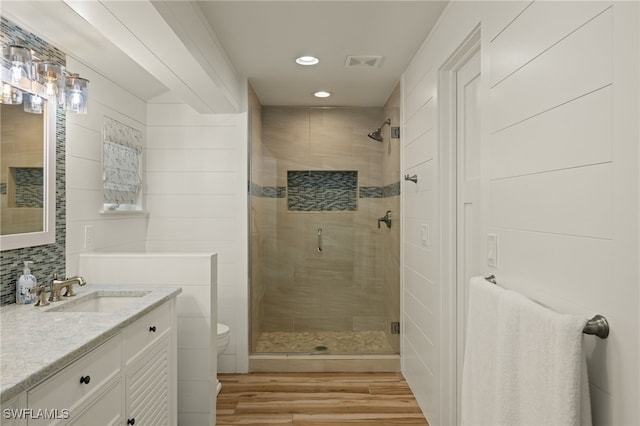 bathroom with toilet, hardwood / wood-style floors, vanity, and walk in shower