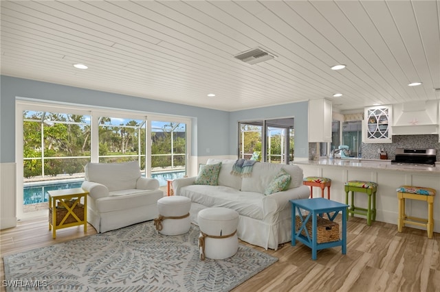 living room with light wood-type flooring, wood ceiling, and sink