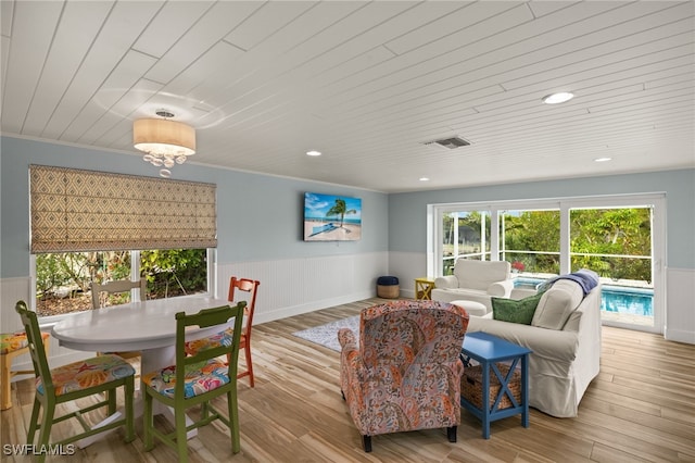 living room featuring ornamental molding, light wood-type flooring, and wooden ceiling