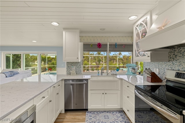 kitchen with white cabinets, appliances with stainless steel finishes, backsplash, and premium range hood