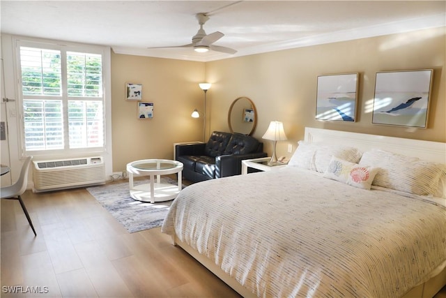 bedroom with hardwood / wood-style floors, a wall unit AC, and ceiling fan