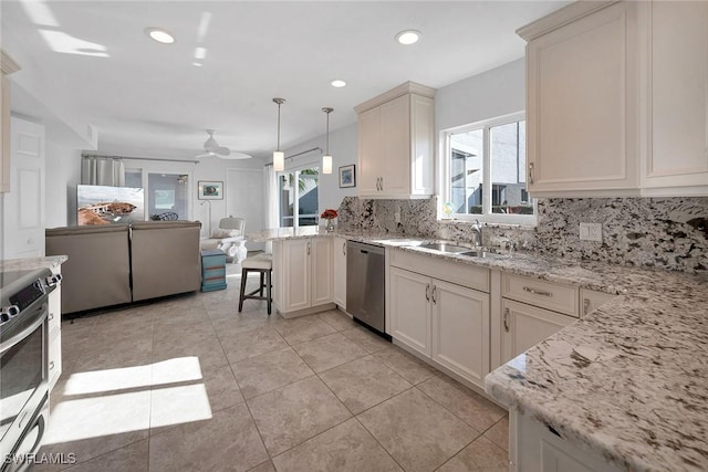 kitchen featuring appliances with stainless steel finishes, a breakfast bar, ceiling fan, sink, and pendant lighting