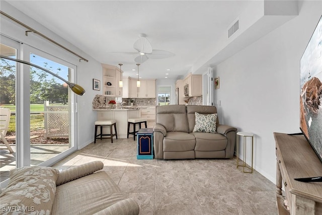 living area with ceiling fan, visible vents, and baseboards