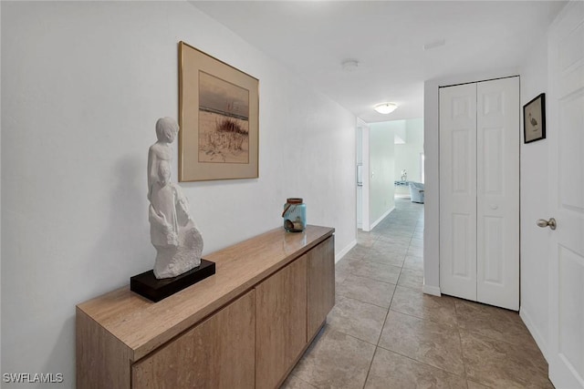 corridor featuring light tile patterned flooring and baseboards