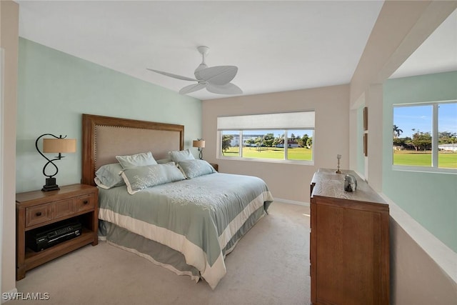 bedroom with light carpet, multiple windows, a ceiling fan, and baseboards