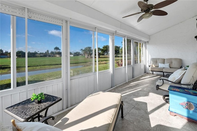 sunroom featuring a ceiling fan, a water view, and vaulted ceiling