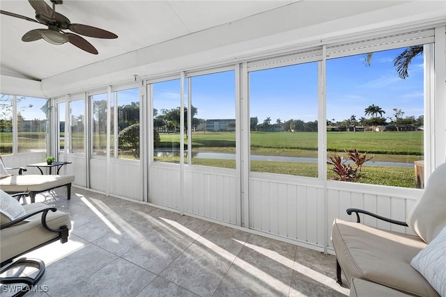 sunroom featuring lofted ceiling, a water view, and a ceiling fan