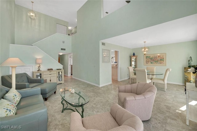 living area with visible vents, a high ceiling, baseboards, and a notable chandelier