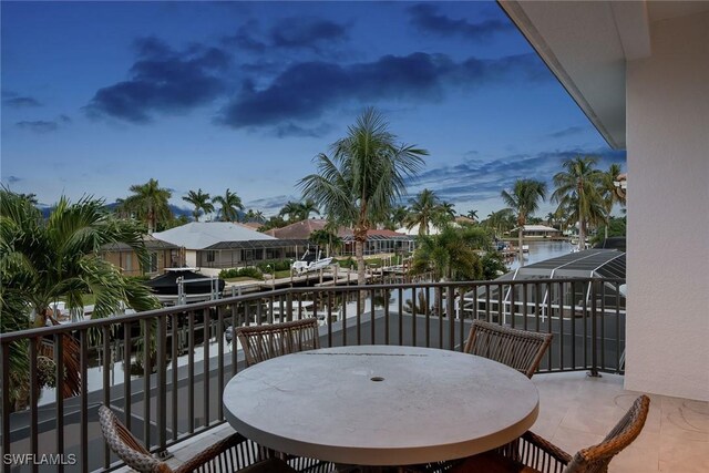 balcony at dusk featuring a water view