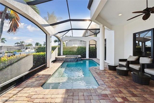 view of pool with an in ground hot tub, pool water feature, ceiling fan, and a lanai