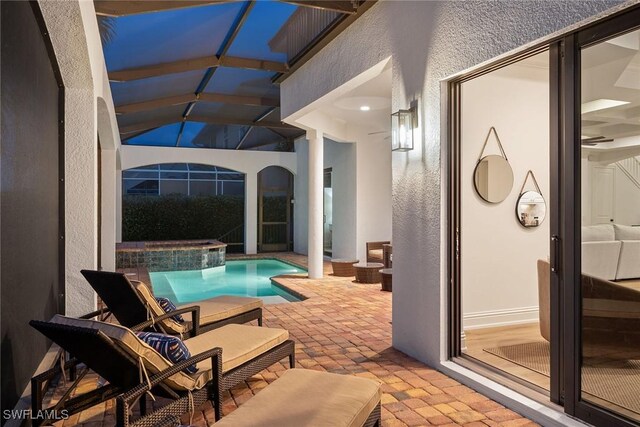 view of swimming pool featuring an in ground hot tub, glass enclosure, and a patio area