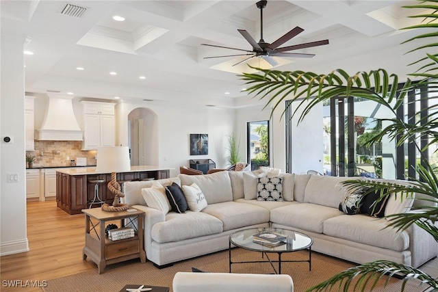 living room featuring ceiling fan, beam ceiling, light hardwood / wood-style flooring, and coffered ceiling