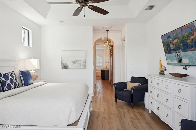 bedroom featuring a tray ceiling, ceiling fan, and light wood-type flooring