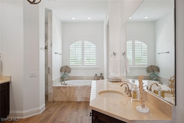 bathroom with vanity, wood-type flooring, and tiled bath