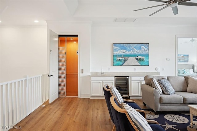 living room featuring light hardwood / wood-style floors, wine cooler, ornamental molding, and sink