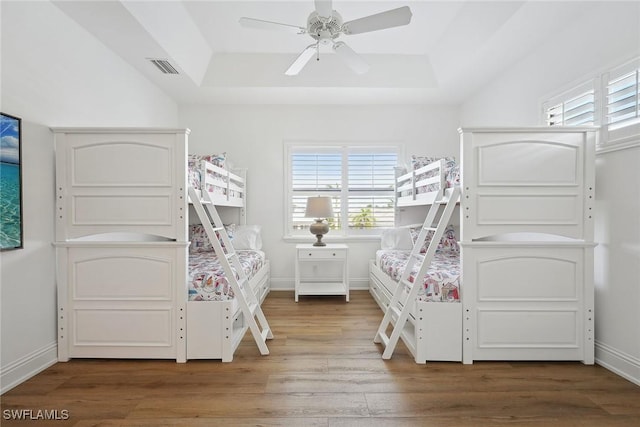 unfurnished bedroom featuring hardwood / wood-style floors, ceiling fan, and a tray ceiling