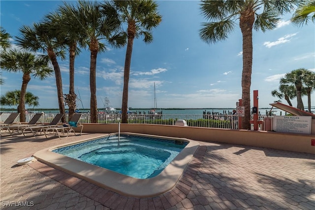 view of swimming pool featuring a community hot tub, a patio, and a water view