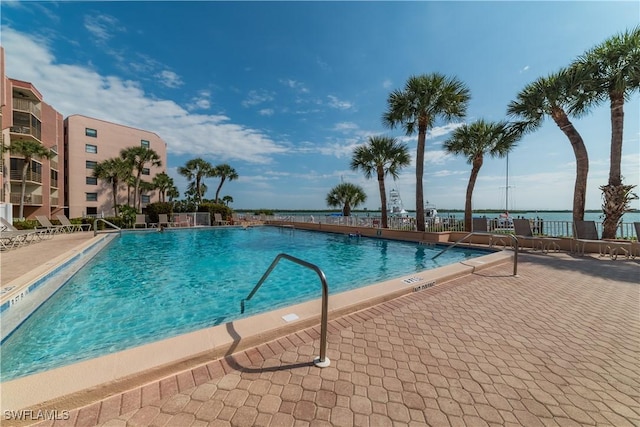 view of pool with a patio and a water view