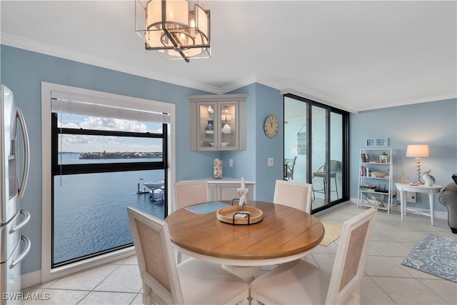 tiled dining room with a water view, ornamental molding, and a chandelier