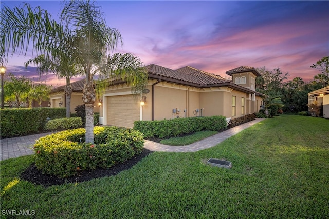 property exterior at dusk with a garage and a lawn