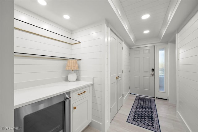 mudroom featuring a raised ceiling, wine cooler, and light hardwood / wood-style flooring