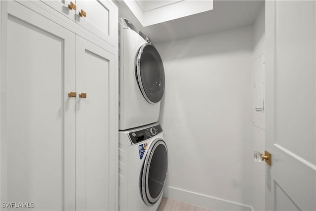 laundry room featuring cabinets and stacked washer / dryer