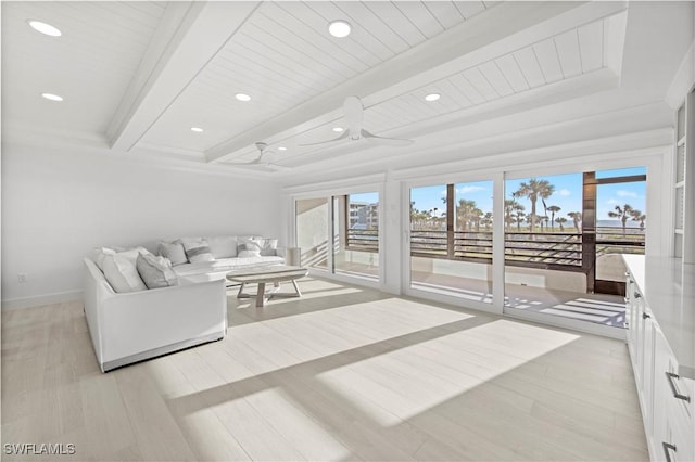 living room with a wealth of natural light, ceiling fan, beamed ceiling, and light wood-type flooring