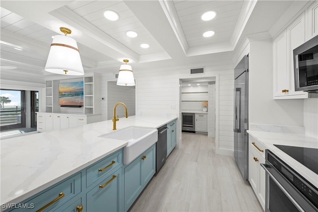 kitchen with blue cabinetry, sink, white cabinets, and decorative light fixtures