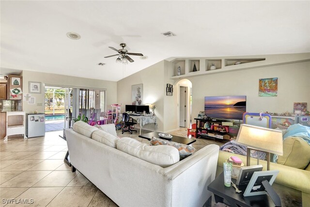 living room featuring ceiling fan, light tile patterned floors, and vaulted ceiling