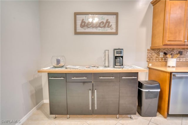 bar featuring tasteful backsplash, light tile patterned flooring, and stainless steel dishwasher