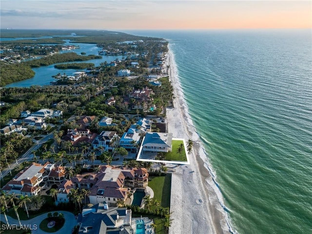 aerial view at dusk featuring a beach view and a water view