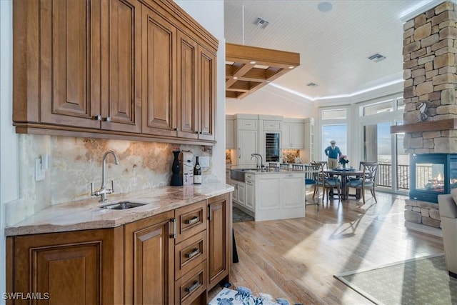 kitchen with backsplash, a fireplace, light hardwood / wood-style floors, and sink